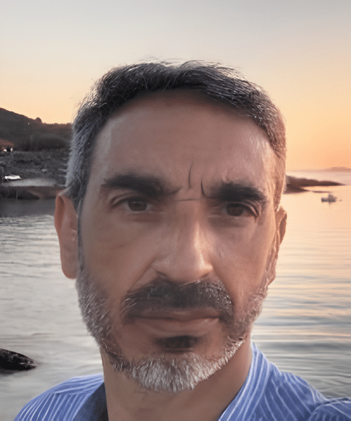 A photo of Luis Sánchez Álvarez standing with the shore of the sea behind him at sunset.